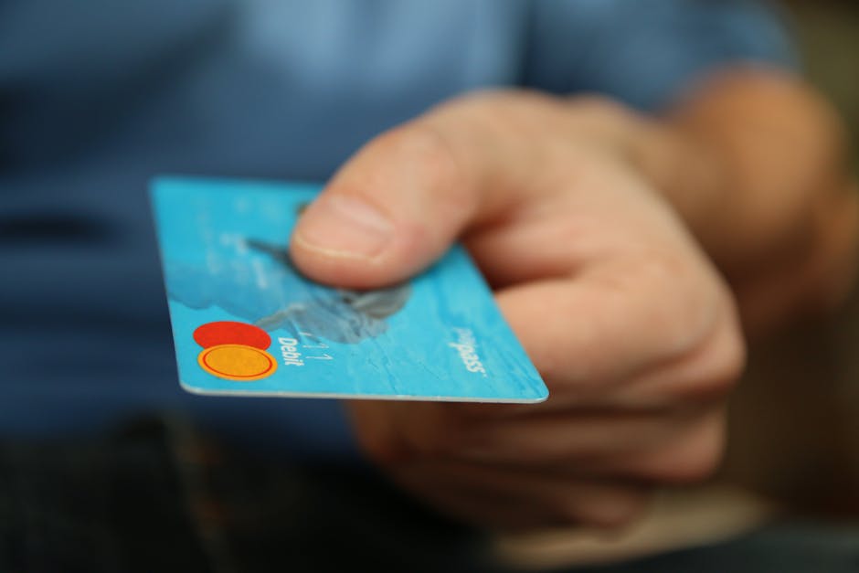 Close-up of a hand holding a blue credit card, symbolizing modern digital payments